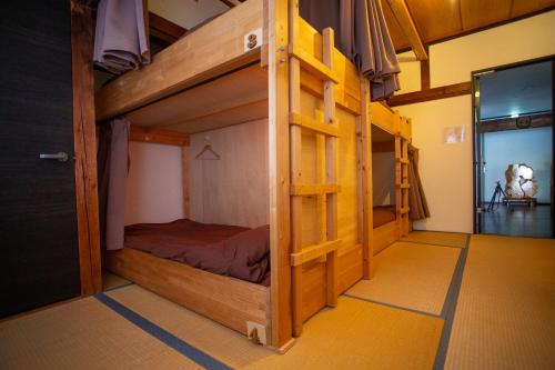 a bedroom with a bunk bed with a ladder at Kominka Guesthouse SENTŌ in Yakumo
