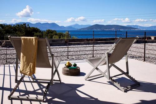 two chairs sitting on a balcony with a view of the ocean at Nikolaou Art Residence in Aegina Town