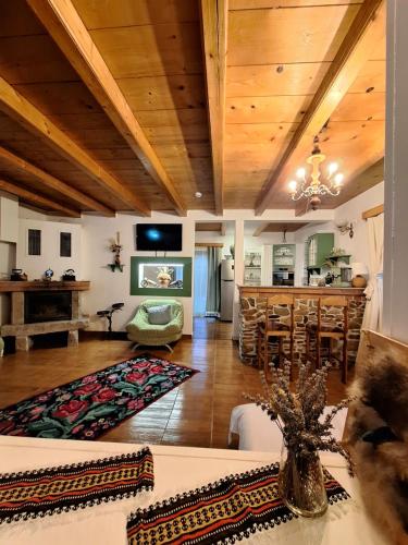 a living room with a wooden ceiling and a kitchen at Clematis House in Voronet