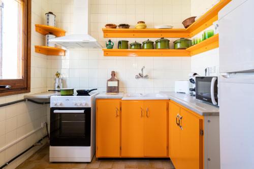 a kitchen with orange cabinets and a stove at Cozy house in Priorat! Barbecue & Relax - Climbing & Views in Poboleda