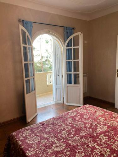 a bedroom with a bed and an open door at villa vue mer plage sghirat in Benhammouch