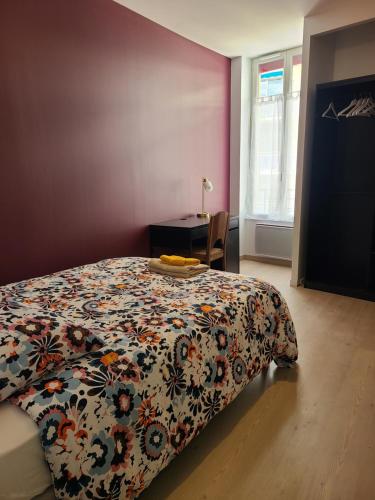 - une chambre avec un lit avec un couvre-lit floral et un bureau dans l'établissement APPT CENTRE VILLE GARE HOPITAL IUT, à Roanne