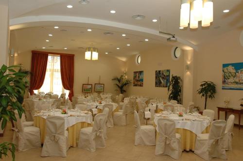 a banquet hall with white tables and white chairs at Le Cheminée Business Hotel Napoli in Naples