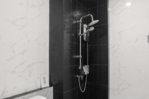 a shower with a black tiled wall and a shower at De Piraya residence in Ban Bo Sai Klang