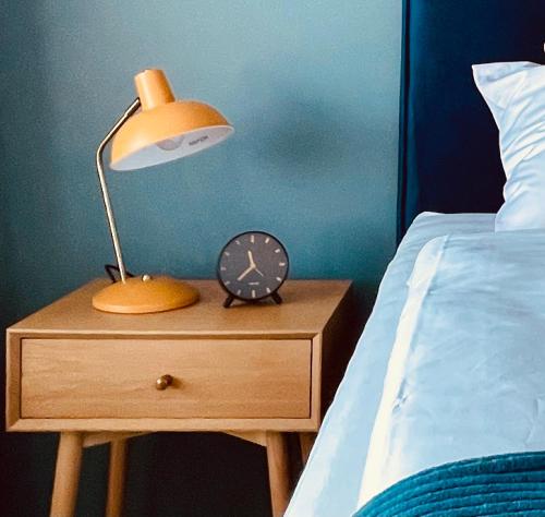 a lamp and a clock on a night stand next to a bed at SmartApartment Prúdy Trnava, Free Parking, 800m CityArena in Trnava