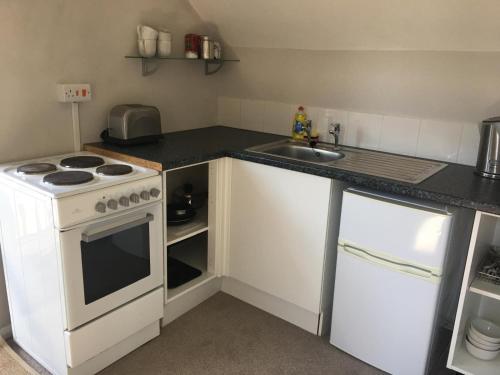 uma pequena cozinha com um fogão e um lavatório em Oxfordshire Village Apartment em Rotherfield Peppard