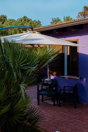 a patio with two chairs and a white umbrella at Funtana'e Mari in Gonnesa