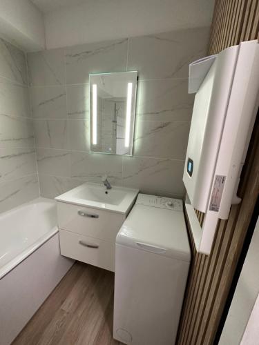une salle de bain blanche avec un lavabo et un miroir dans l'établissement Le Bonamour sur le port de Capbreton, à Capbreton