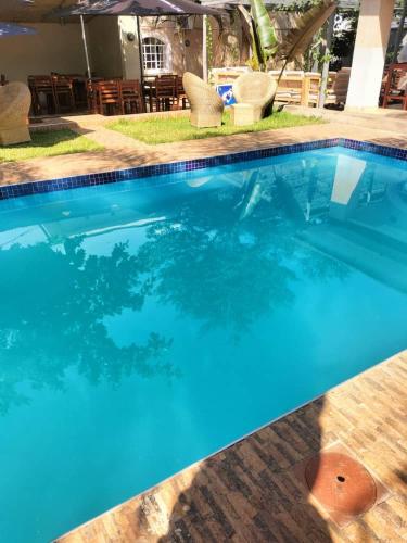a blue swimming pool with chairs and an umbrella at Mpatsa Quest Hotels in Lilongwe
