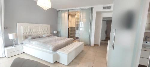 a white bedroom with a white bed and a bathroom at Amazing sea view Penthouse close to beach in Ashdod