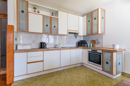 a kitchen with white cabinets and a sink at Holiday apartment Kali - Ugljan island in Kali