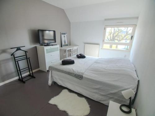 a white bedroom with a bed and a television at Appartement terrasse in Saint-Jean-de-Daye