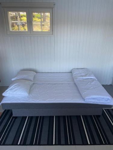 a bed in a white room with two windows at Edvin rantamökki in Taalintehdas