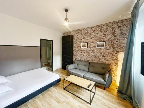 - une chambre avec un lit, un canapé et un mur en briques dans l'établissement L'industriel de Kléber - Gare - Netflix - Calme, à Toulouse