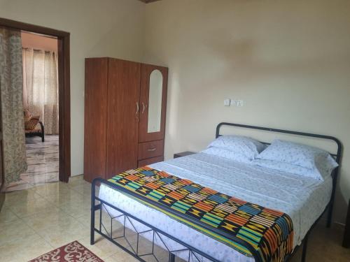 a bedroom with a bed with a dresser and a mirror at Cozy Escape in Accra by Manna Hospital in Accra