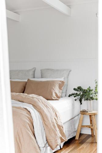 a bedroom with a bed with white walls and a table at Cape Beach House in Byron Bay