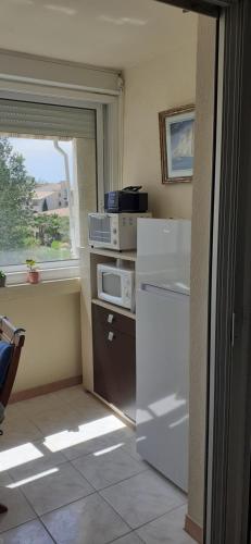 une cuisine avec un réfrigérateur blanc et une fenêtre dans l'établissement Charmant Studio Centre Port du Cap d'Agde, au Cap d'Agde