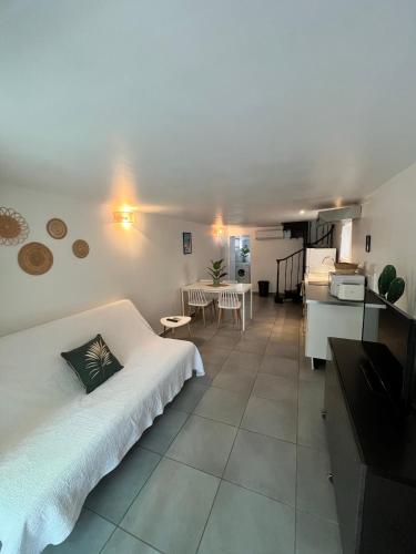 un salon avec un lit blanc et une cuisine dans l'établissement La bambouseraie de La mitre, à Toulon