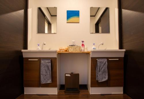 a bathroom with two sinks and two mirrors at Kominka Guesthouse SENTŌ in Yakumo