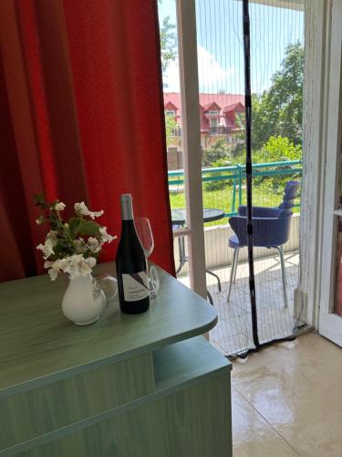 a bottle of wine and a vase with flowers on a table at Lelle Beach Club in Balatonlelle