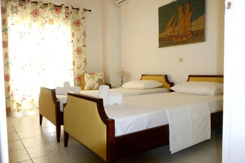 Cette chambre comprend 2 lits, une table et une fenêtre. dans l'établissement Arco In Pietra, à Apolakkiá