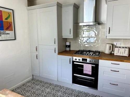 a kitchen with white cabinets and a stove top oven at 2 Bedroom City Centre House - Pet Friendly - Free Parking in Cardiff