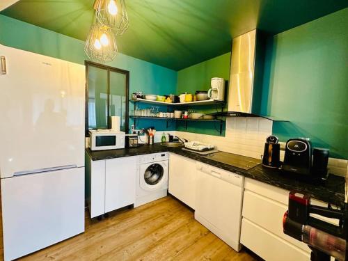une cuisine aux murs verts et un lave-linge/sèche-linge. dans l'établissement Fonctionnel - 2 chambres - bien situé à 300m de la Plage - Parking Privé de Juin à Sept, à Canet