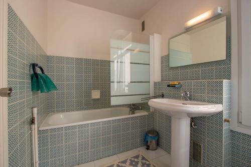 une salle de bain avec un lavabo, une baignoire et un miroir dans l'établissement Residence Erdian, à Hendaye