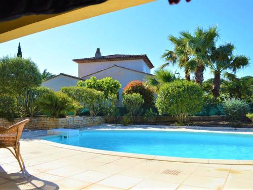 une piscine devant une maison avec des palmiers dans l'établissement Maison avec piscine couverte et terrasse barbecue - 6 couchages - Sainte Maxime - FR-1-226-311, à Sainte-Maxime