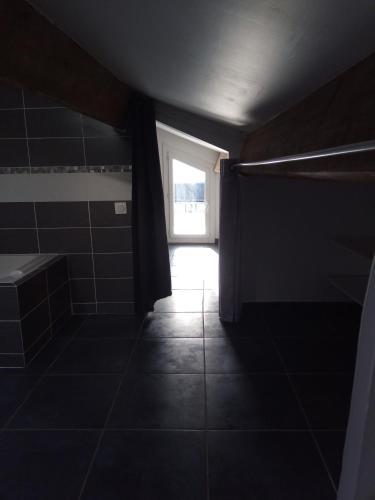 une salle de bain sombre avec une fenêtre et un sol carrelé dans l'établissement T3 Terrasse vue Cathédrale Climatisé, à Narbonne