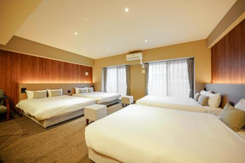 a hotel room with three beds and a couch at Nico Hotel in Osaka