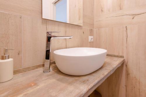 a bathroom with a white bowl sink on a wooden counter at Domo Green House in Villasimius