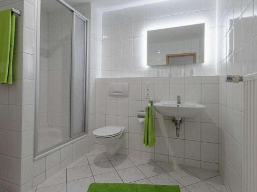 a white bathroom with a toilet and a sink at Strandeck Zuidstrand in Göhren