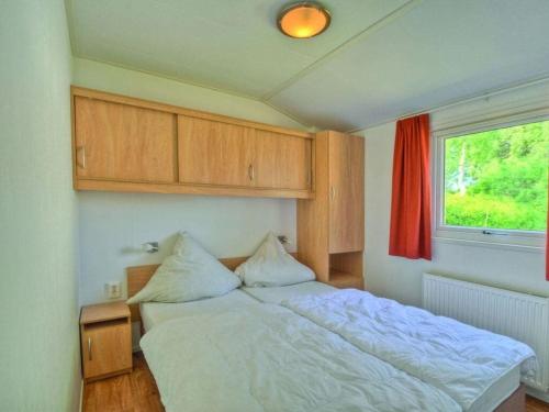 a bedroom with a white bed and a window at - The "Ocala" mobile home in Fehmarn