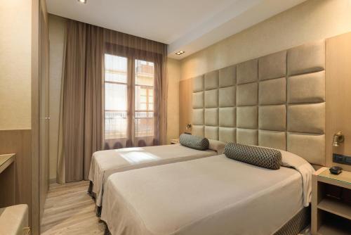a bedroom with two beds and a window at Hotel Suizo in Barcelona