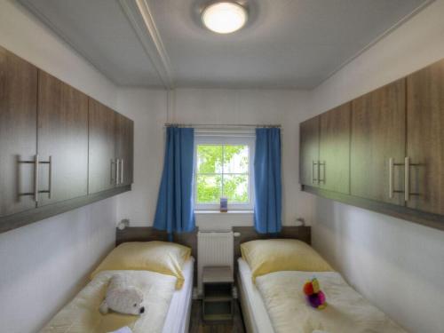 a bedroom with two beds and a window with blue curtains at Holiday House 177 Seeadler "Sea Eagle" type in Fehmarn