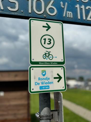 two signs on a pole with a bike sign at LODGE, een super knus tiny house, nabij vaarwater en haven! in Belt-Schutsloot