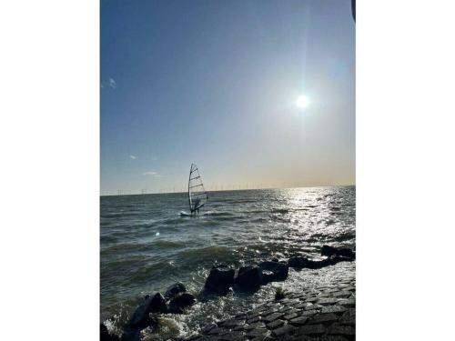 a sail boat in the ocean with the sun in the sky at Sunhouse Makkum Beach in Makkum