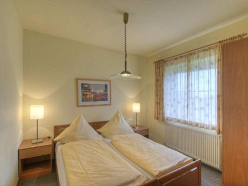 a bedroom with a bed with two lamps and a window at Comfortable holiday residence in Fehmarn