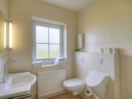 a bathroom with a toilet and a sink and a window at Comfortable holiday residence in Fehmarn