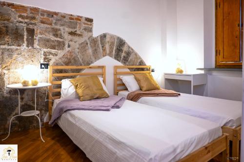 two beds in a room with a brick wall at Inn Pisa Rentals 2- In The Heart of Pisa in Pisa