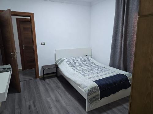 un pequeño dormitorio con una cama con una manta. en El-Shaikh Zayed, 6 october 3BHK flat- families only en Sheikh Zayed