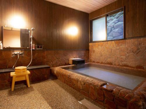 een badkamer met een groot bad en een raam bij Wafu Ryokan Misato in Minamioguni