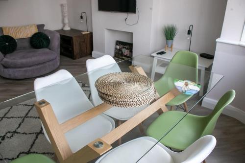 sala de estar con mesa de cristal y sillas verdes en Coastal Haven in Leigh-on-Sea en Southend-on-Sea