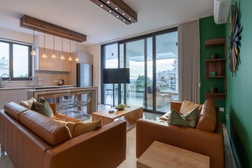 a living room with two brown couches and a kitchen at Beachcomber 2-Bedroom Apartment in Larnaca in Larnaca