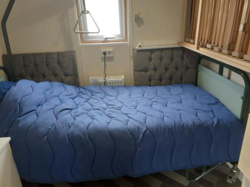 uma cama azul num quarto com uma janela em NV 1219 - Beach Resort Nieuwvliet Bad em Nieuwvliet
