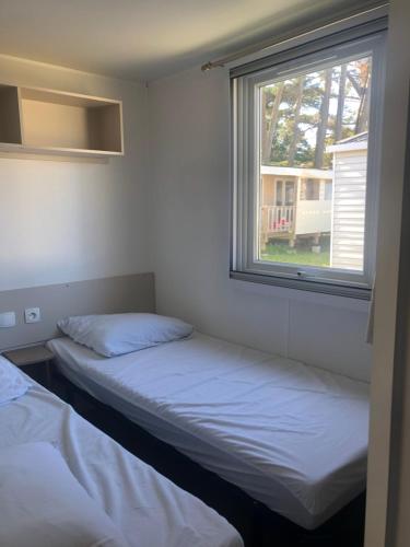 2 camas en una habitación con ventana en Mobil Home vue mer, en Quiberon