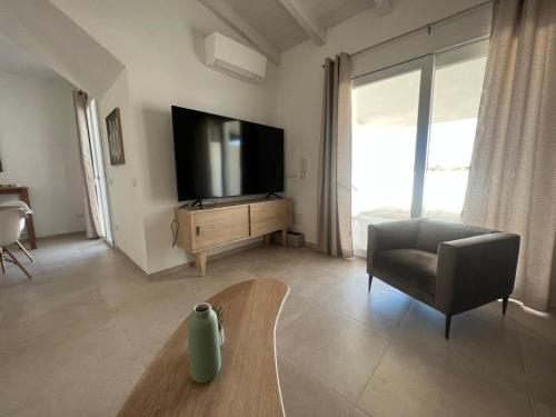 sala de estar con TV, silla y mesa en La Casa di Spinosella, en Valledoria