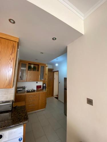 a kitchen with wooden cabinets and a white wall at 2 Bedroom Apartment, Zygos Centre Block D - By IMH Travel & Tours in Paphos City