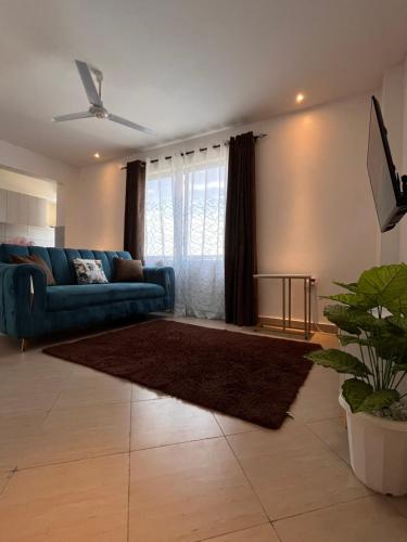 - un salon avec un canapé bleu et un tapis dans l'établissement Haller Park Pasific Apartments Bamburi, à Mombasa